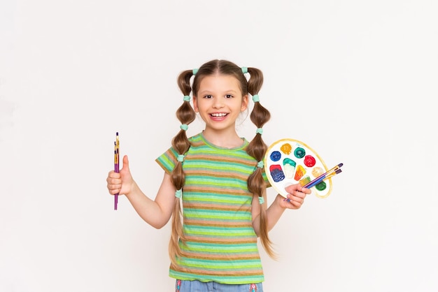 A young artist with a palette of paints for brushes for drawing on a white isolated background