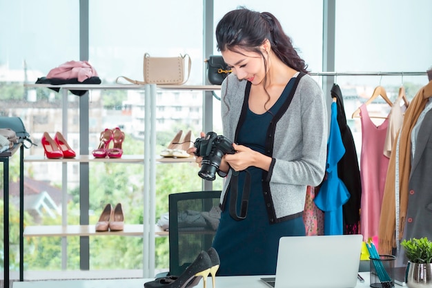 Young Asia beautiful woman taking a photo and working online e-commerce shopping at clothes shop.