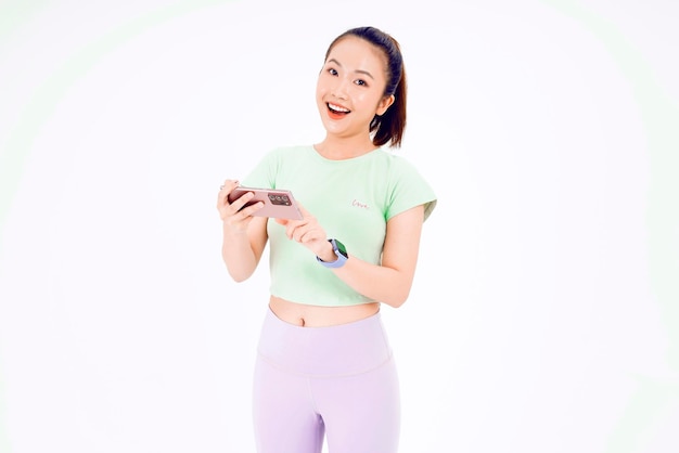 Young Asia lady show empty smart phone screen with positive expression smiles broadly dressed in casual clothing feeling happiness on blue background Mobile phone with white screen in female hand