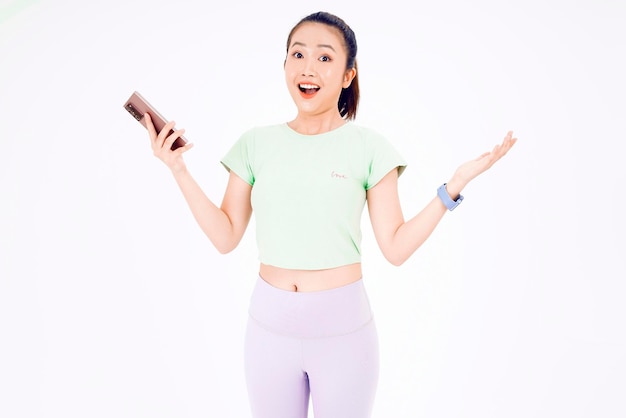 Young Asia lady show empty smart phone screen with positive expression smiles broadly dressed in casual clothing feeling happiness on blue background Mobile phone with white screen in female hand