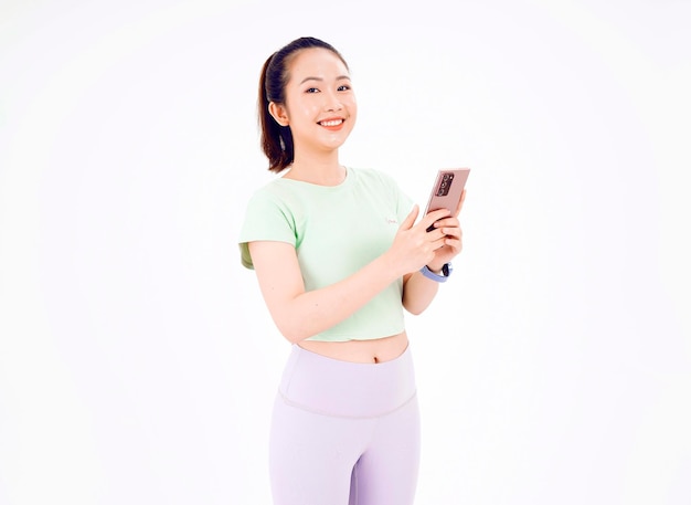 Young Asia lady show empty smart phone screen with positive expression smiles broadly dressed in casual clothing feeling happiness on blue background Mobile phone with white screen in female hand