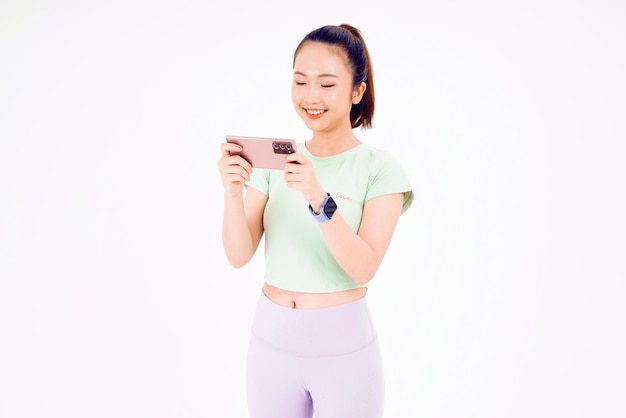 Young Asia lady show empty smart phone screen with positive expression smiles broadly dressed in casual clothing feeling happiness on blue background Mobile phone with white screen in female hand