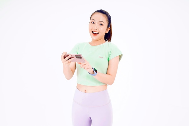 Young Asia lady show empty smart phone screen with positive expression smiles broadly dressed in casual clothing feeling happiness on blue background Mobile phone with white screen in female hand