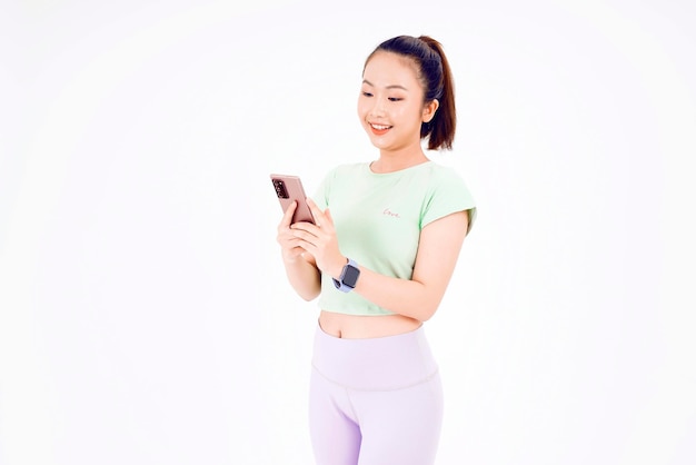 Young Asia lady show empty smart phone screen with positive expression smiles broadly dressed in casual clothing feeling happiness on blue background Mobile phone with white screen in female hand