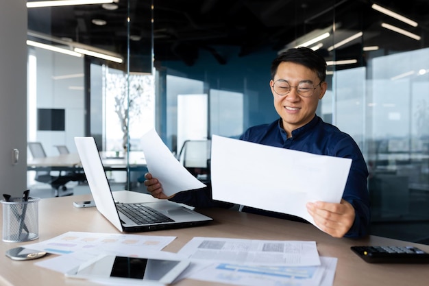 A young asian architect designer engineer sitting at the desk in the office holding papers works