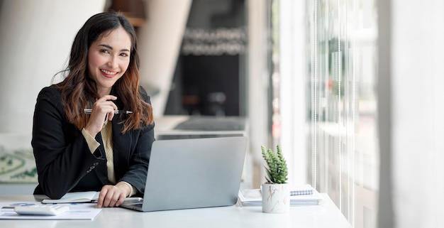 Young asian beautiful and charming busineswoman smiling and working on laptop computer at office