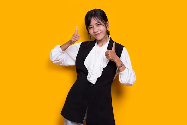 young asian beautiful woman with ok sign gesture tumb up isolated on yellow background