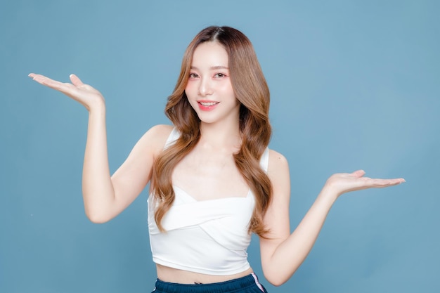 Young Asian beauty woman curly long hair with korean makeup style on face and perfect clean skin showing open hand palm on isolated blue background Facial treatment Cosmetology plastic surgery