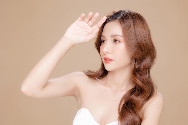 Young Asian beauty woman curly long hair with korean makeup style on face and perfect skin on isolated beige background Facial treatment Cosmetology plastic surgery