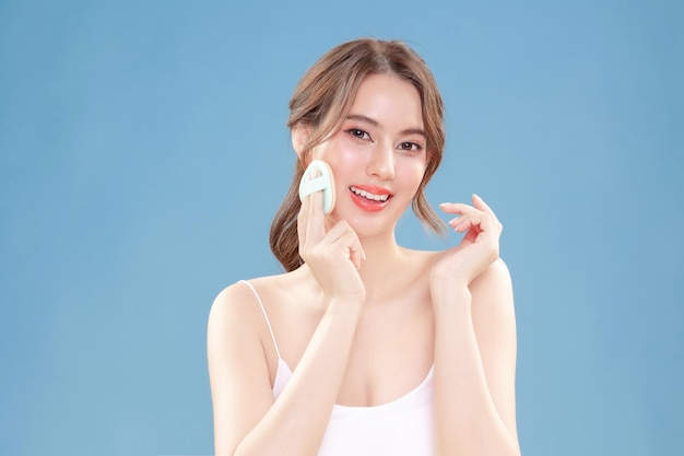 Young Asian beauty woman pull back hair with Koreans makeup style on face and perfect clean skin on isolated blue background Facial treatment Cosmetology plastic surgery