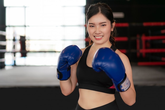 Young Asian Boxing fitness woman smiling happy wearing blue boxing gloves