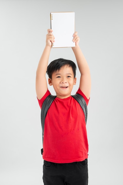 Young Asian boy student holding book and show over head isolated on white background