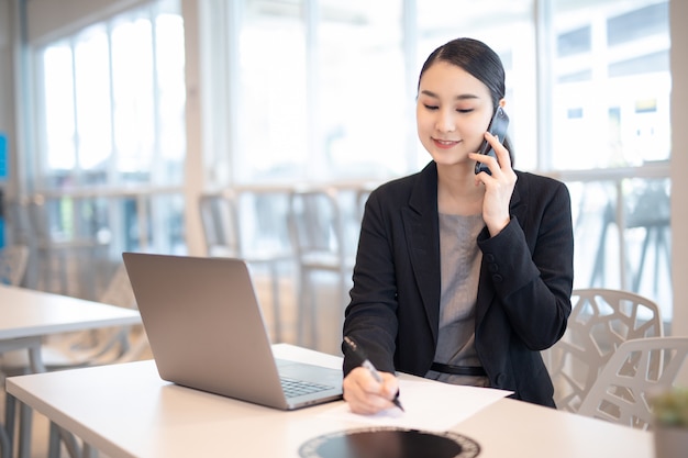 Young Asian business girl working with laptop in coffee shop cafe.