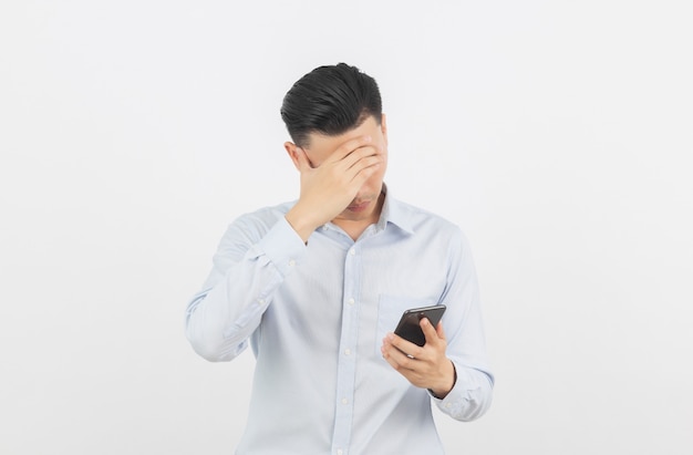 Young asian business man unhappy and frustrated with something on smartphone. Negative facial expression isolated on white