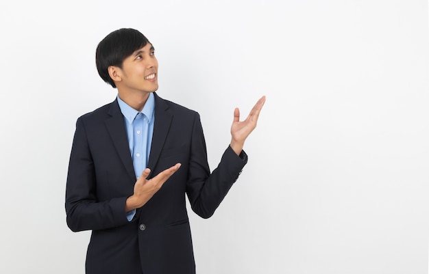 Young asian business man with blue shirt pointing to the side with a hand to present a product or an idea isolated on white background.