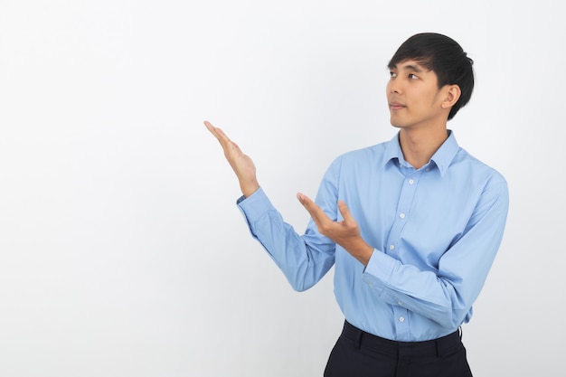 Young asian business man with blue shirt pointing to the side with hands to present a product isolated on white 