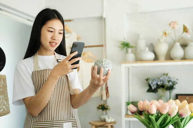 Young asian business owner holding phone and retail package parcel