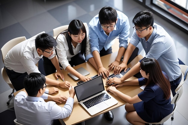 Young Asian business team work together in project brainstorm meeting using laptop computer Colleague coworker startup office or people teamwork concept Top view banner size with copy space