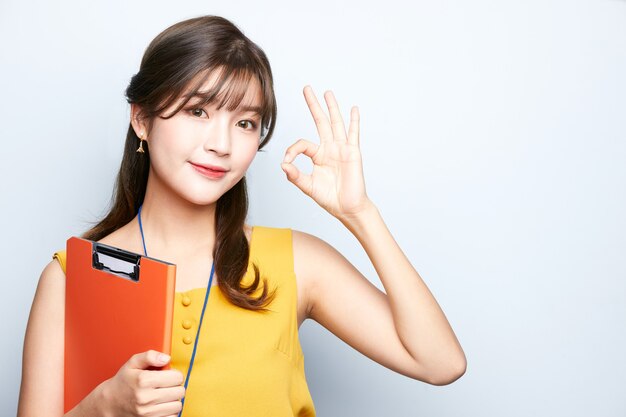 young asian business woman is  showing ok sign and holding a document folder isolated background