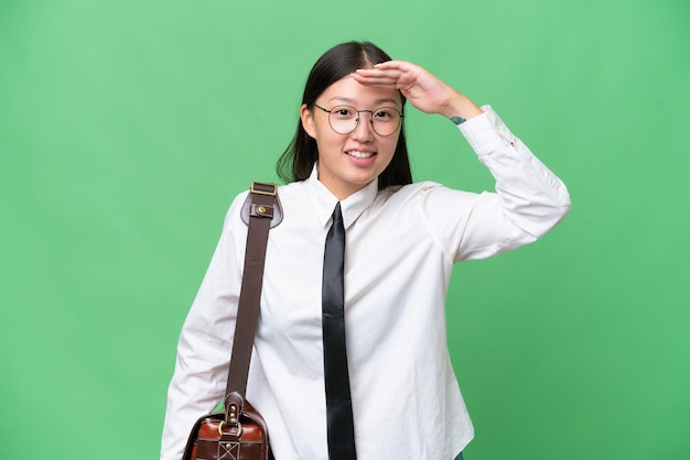 Young Asian business woman over isolated background looking far away with hand to look something