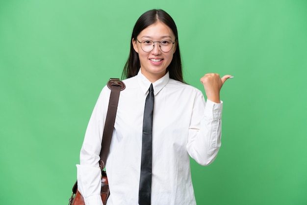 Young Asian business woman over isolated background pointing to the side to present a product