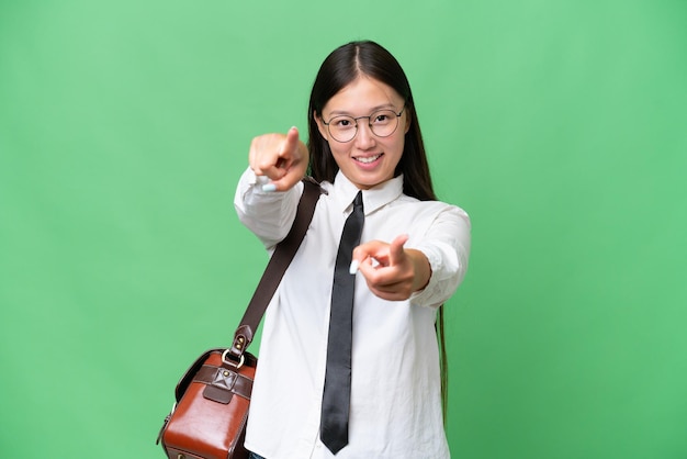 Young Asian business woman over isolated background points finger at you while smiling