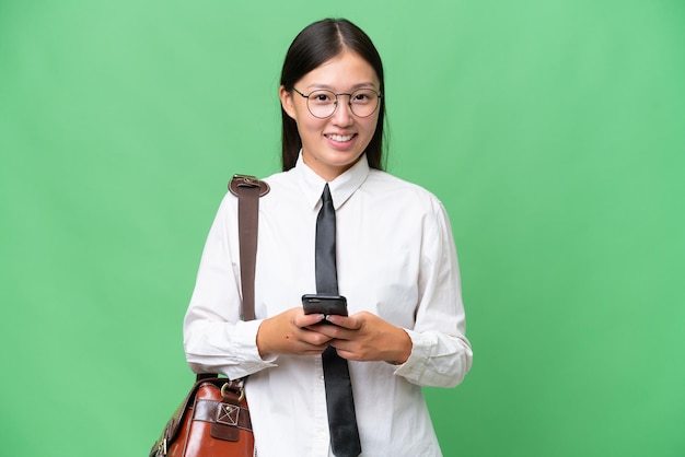 Young Asian business woman over isolated background sending a message with the mobile