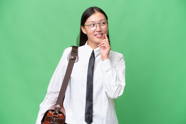 Young Asian business woman over isolated background thinking an idea while looking up