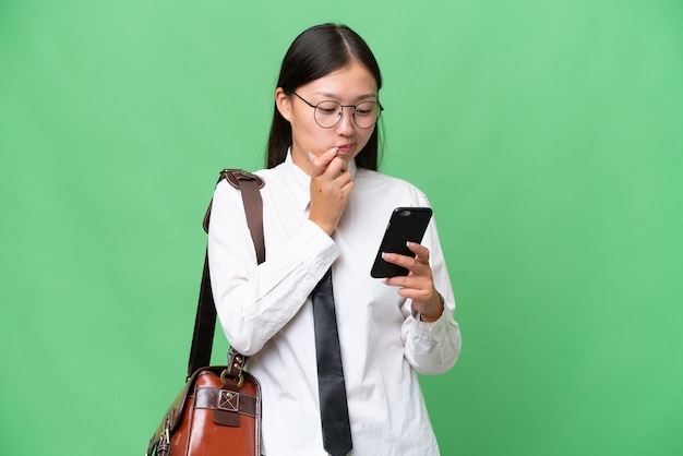 Young Asian business woman over isolated background thinking and sending a message