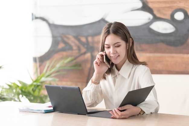 Young Asian Business woman using phone in modern office