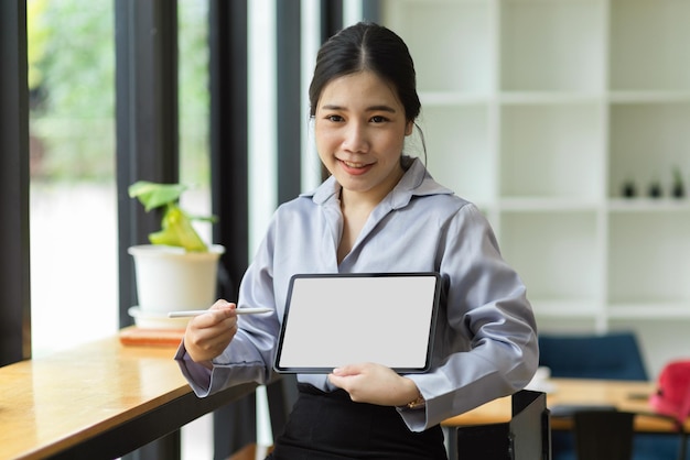 Young asian business worker holding and showing digital tablet computer with blank screen mockup for montage graphic.