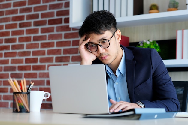 Young asian businessman concentrate on working with laptop computer at office, Asian office man comtemplate on working with laptop computer  business people and office lifestyle 