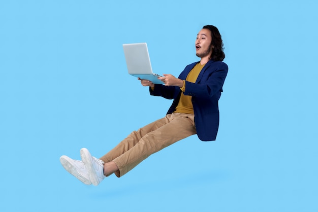 Young asian businessman hand holding computer laptop floating in mid-air isolated on blue space.