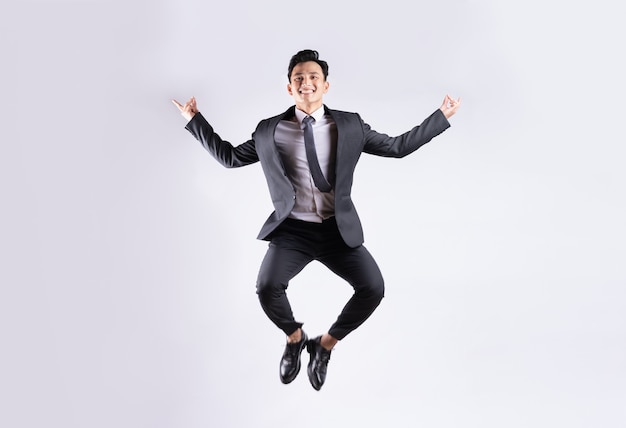 Young Asian businessman jumping on white