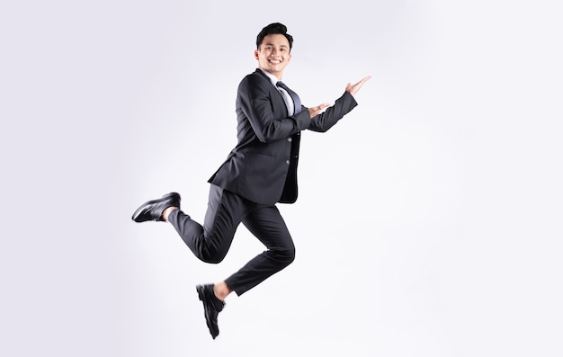 Young Asian businessman jumping on white