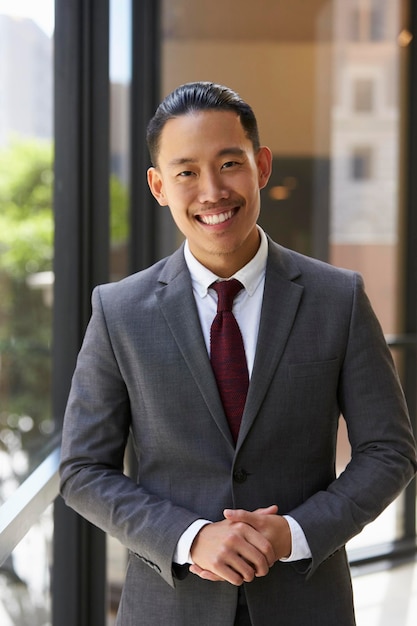 Young Asian businessman smiling to camera vertical