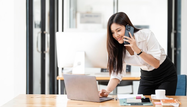 Young asian businesswoman beautiful charming smiling and talking on the mobile phone in the office