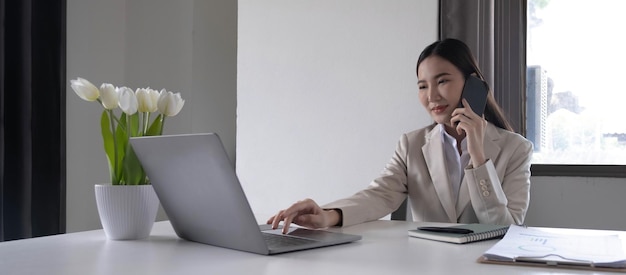 Young asian businesswoman beautiful charming smiling and talking on the mobile phone in the office