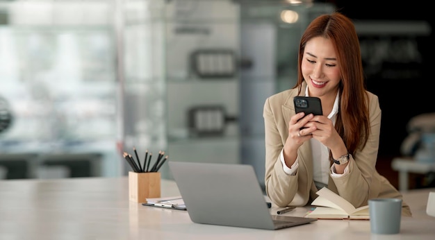 Young asian businesswoman beautiful charming smiling and talking on the mobile phone sitting at the office