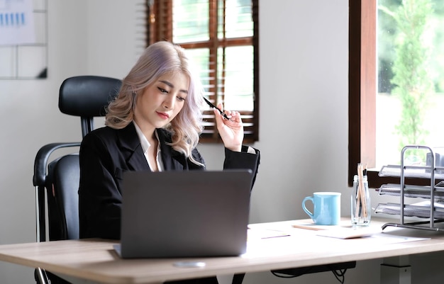 Young asian businesswoman have the pleasure of watching work on their tablet and favorite coffee at the office