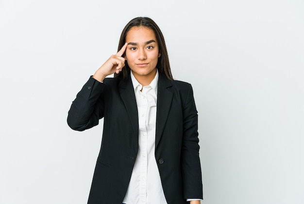 Young asian businesswoman isolated on white wall pointing temple with finger, thinking, focused on a task.