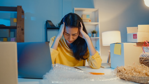 Young asian businesswoman stressed and upset with bad sell in home office at night