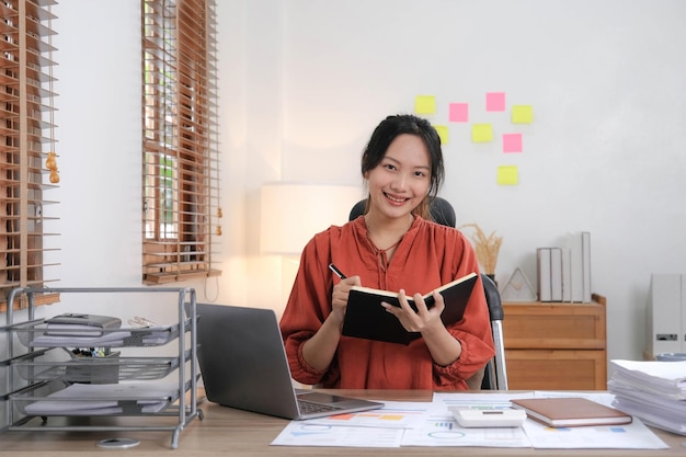 Young Asian businesswoman taking notes using a laptop at the modern office