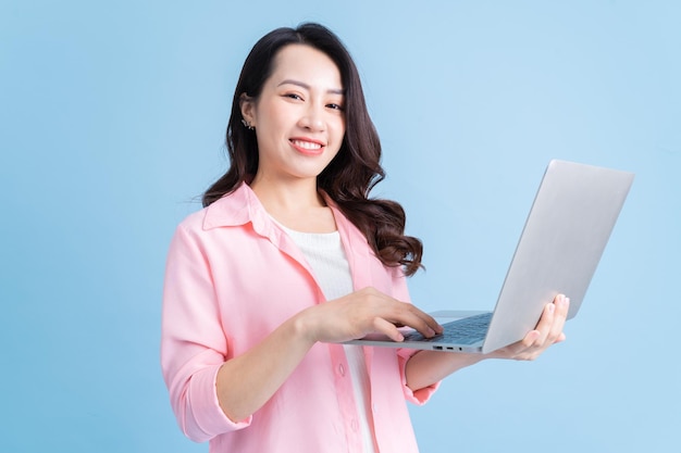 Young Asian businesswoman using laptop on background