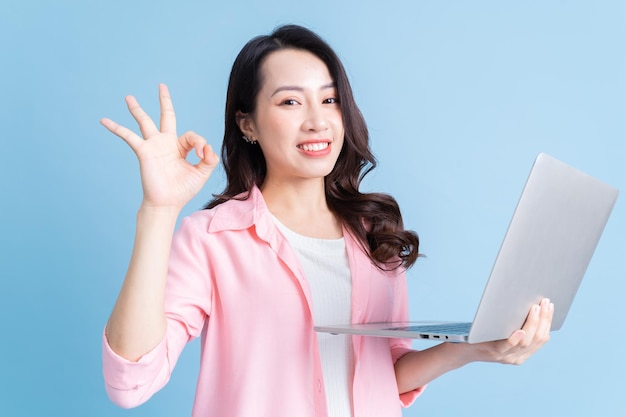 Young Asian businesswoman using laptop on background