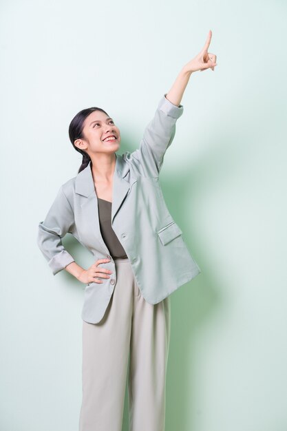 Young Asian businesswoman wearing green suit on green background