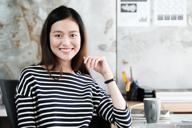 Young asian businesswoman working with with smiling face at office desk, positive emotion, office life concept