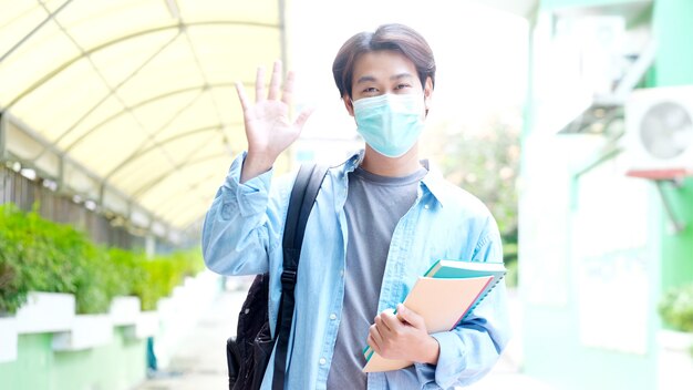 Young asian campus student man wearing protection mask looking at camera