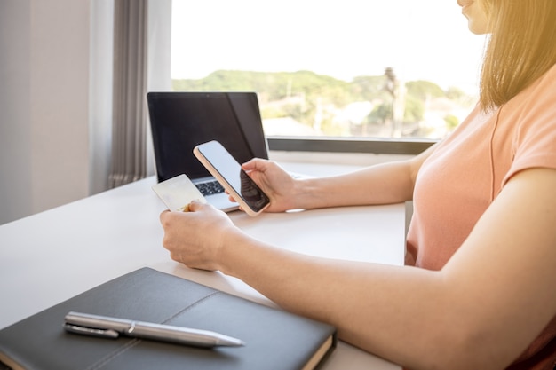 Young Asian consumer woman hand holding a credit card and a smartphone to shop online