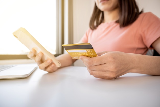 Young Asian consumer woman hand holding a credit card and a smartphone to shop online